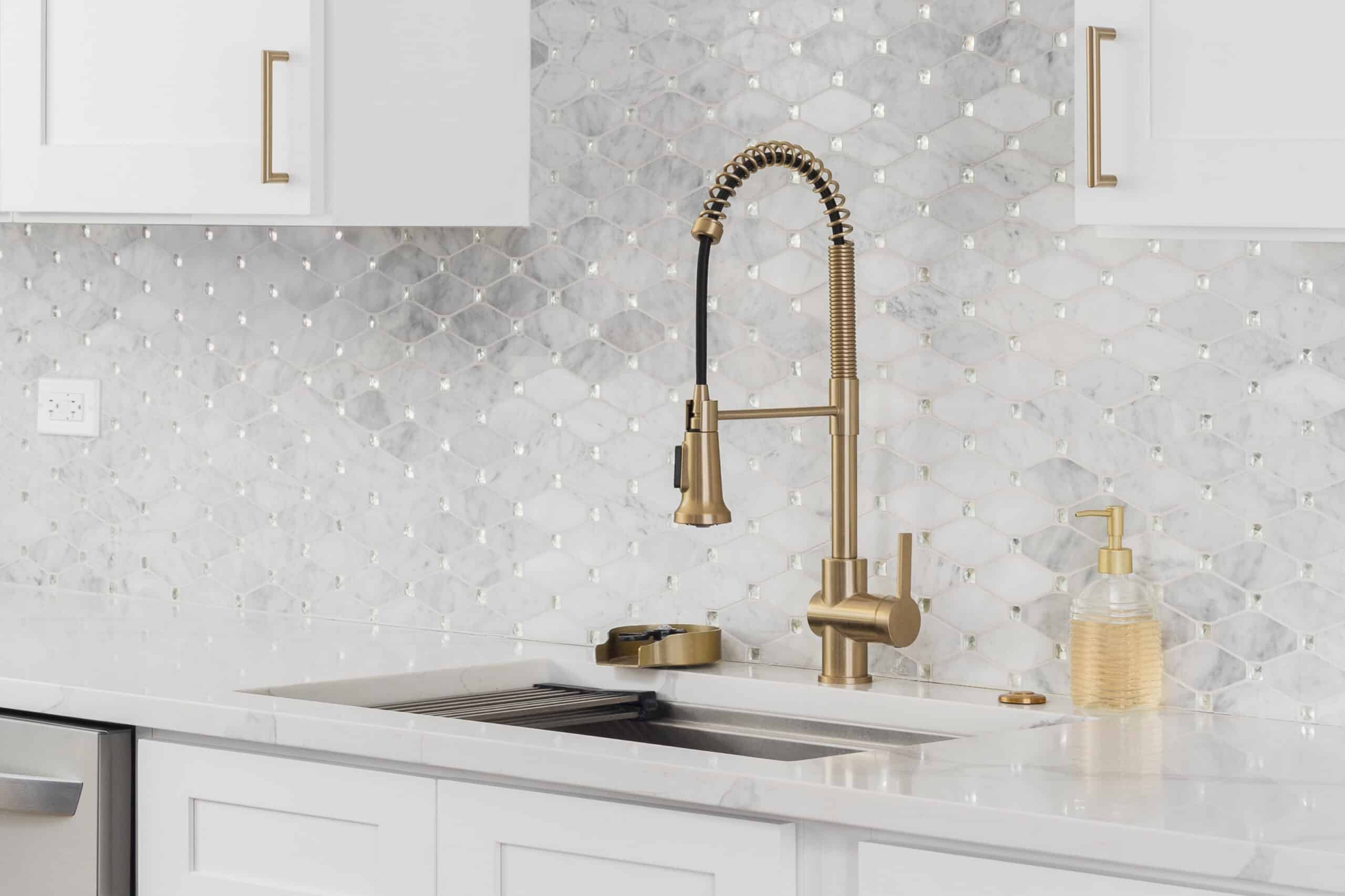Cuisine moderne : robinet laiton brossé, évier inox, comptoir marbre blanc et dosseret mosaïque hexagone incrusté de cristaux.