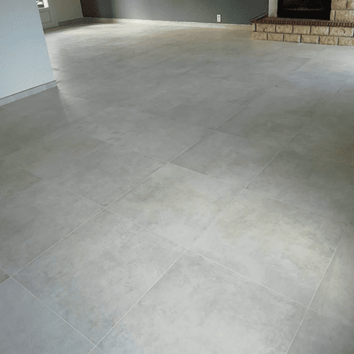 Carrelage Gris Clair Moderne pour Salon avec Cheminée Vaste salon moderne avec grand carrelage gris clair uni et texturé, menant à une cheminée en briques claires.